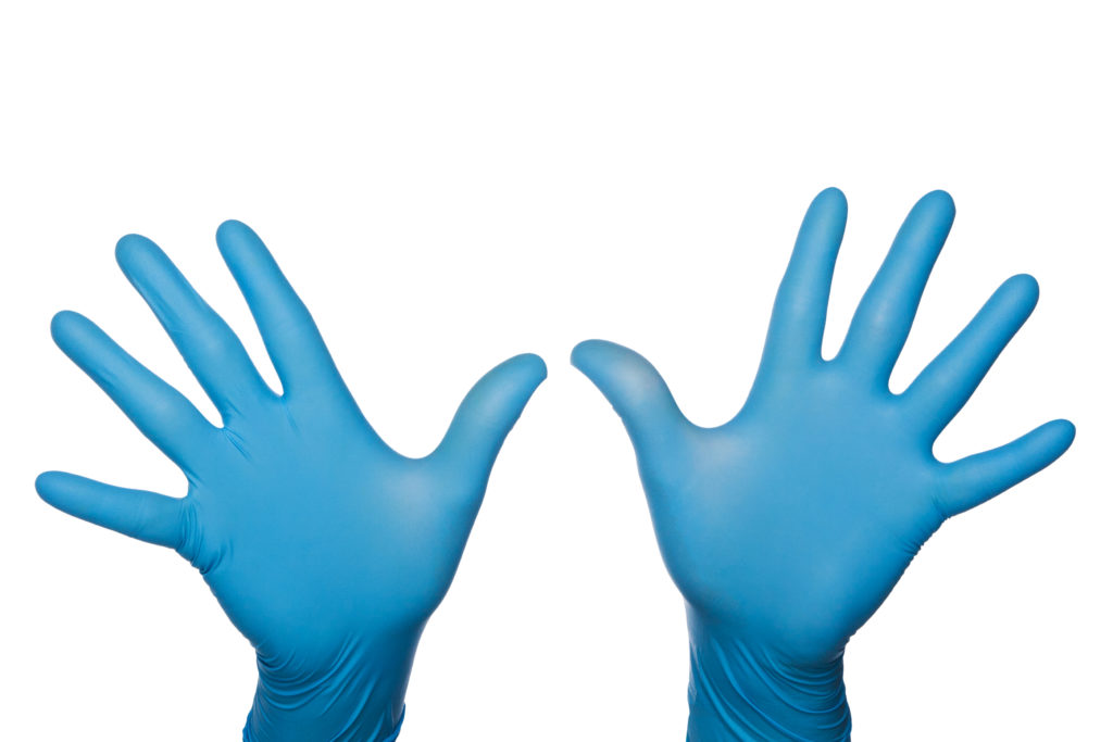 Two blue medical latex gloved hands palms out fingers spread
